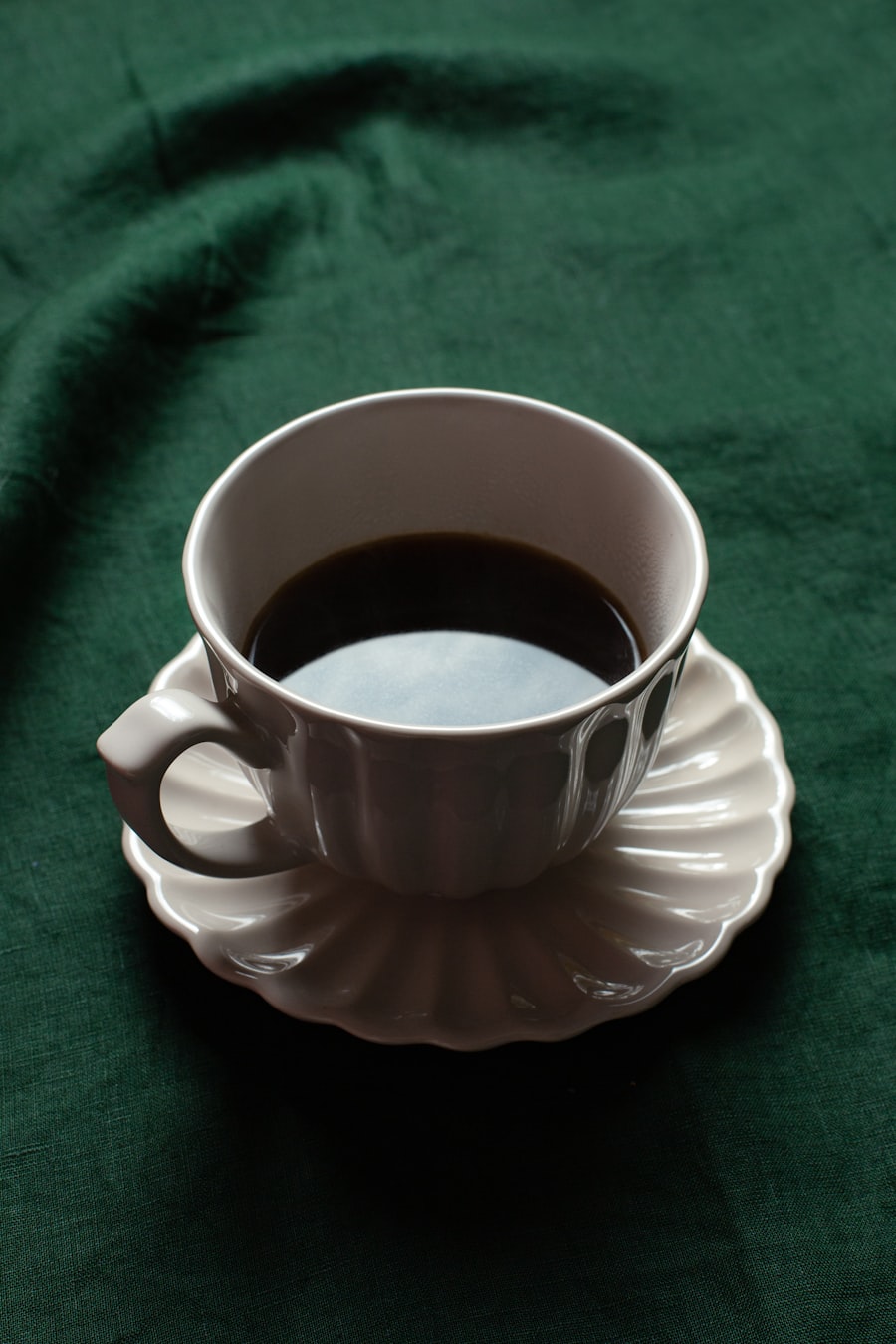 深緑のクロスの上に置かれたブラックコーヒーのカップ
